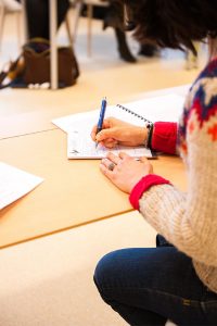 A student taking notes at a classroom desk