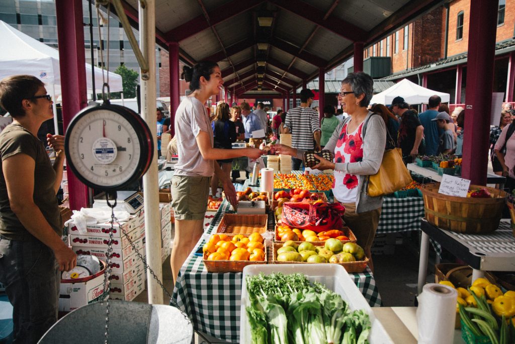 One woman buys produce from another at a farmer's market