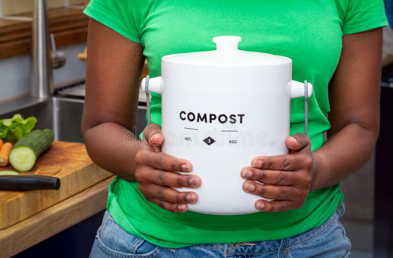 A woman holds a small bin of compost